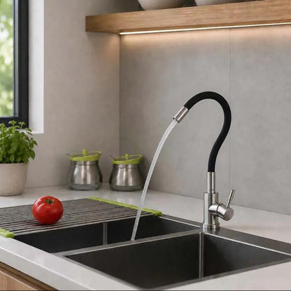A modern kitchen sink setup with a tall curved faucet spraying water, set in a clean kitchen with a double basin, countertop accessories, and a wooden shelf.