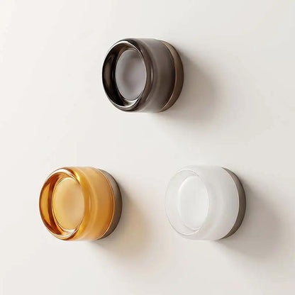 Minimalist Glass Wall Light, three circular glass fixtures in amber, smoky and clear finishes mounted on a pale wall.