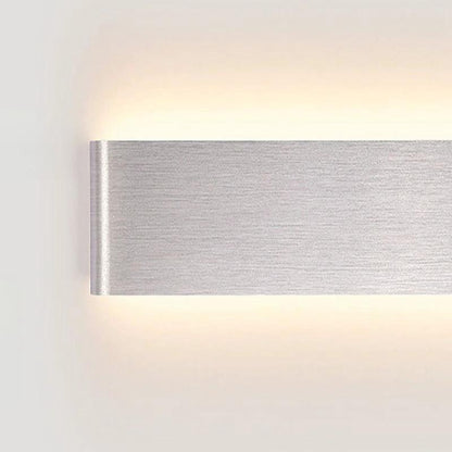 Wall light in brushed aluminium, wall-mounted with up and down LED glow on a white wall.