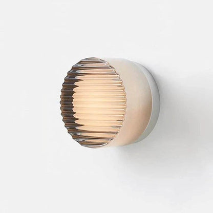 LED Wall Sconce on white wall; amber ribbed glass globe, minimalist metal backplate.