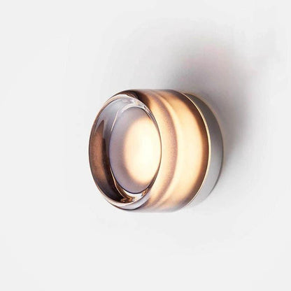 Nordic LED Wall Sconce, copper-toned metal with clear glass ring, warm ambient light on white wall.