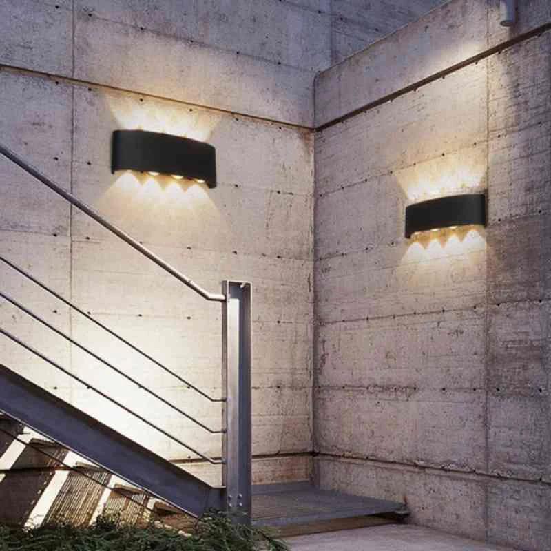Modern Outdoor LED Wall Lamp, two black metal units on an exterior concrete wall beside a stairwell, casting warm light.