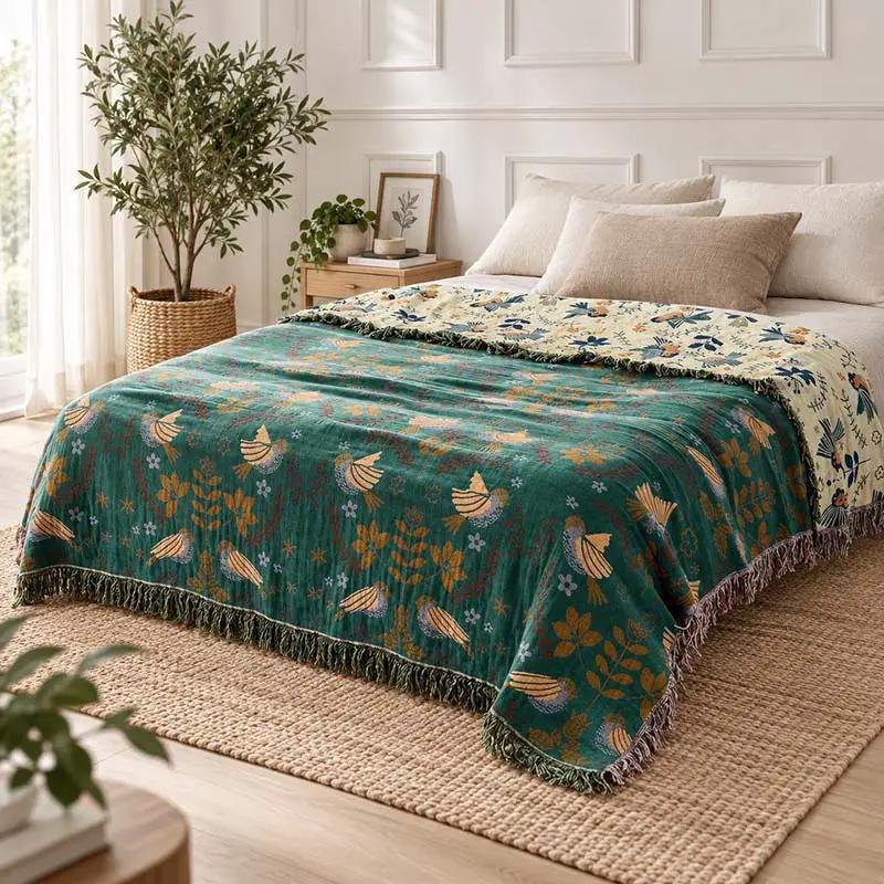 100% Cotton Reversible Throw Blanket used on a bed in a bedroom, teal with bird pattern and fringed edges