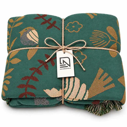 100% Cotton Reversible Throw Blanket with teal bird-pattern print, folded for sofa or bed, Nordic Essentials.