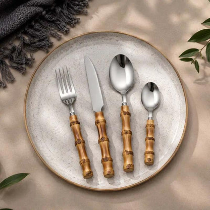 24-Piece Bamboo Handle Cutlery Set on a speckled ceramic plate; four bamboo-handled stainless steel utensils.