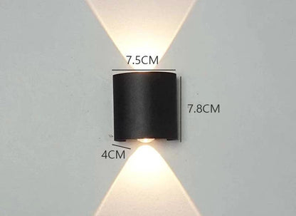 Modern Outdoor LED Wall Lamp, black cylindrical outdoor wall light mounted on a wall, emitting up and down warm light.