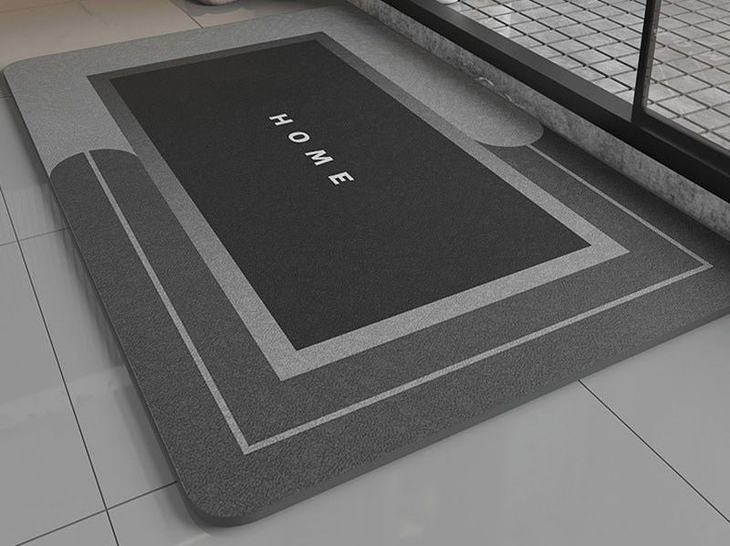 Black bath mat with 'HOME' text on a bathroom floor