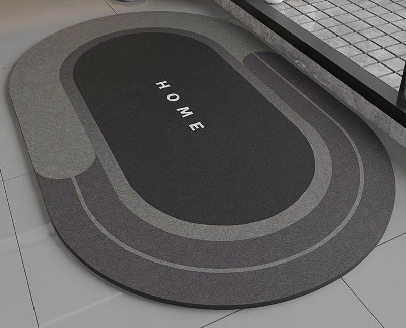 Black bath mat with 'HOME' text on a bathroom floor