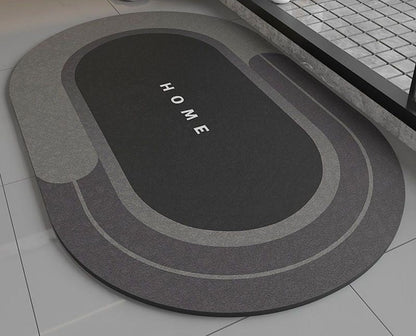 Black bath mat with 'HOME' text on a bathroom floor