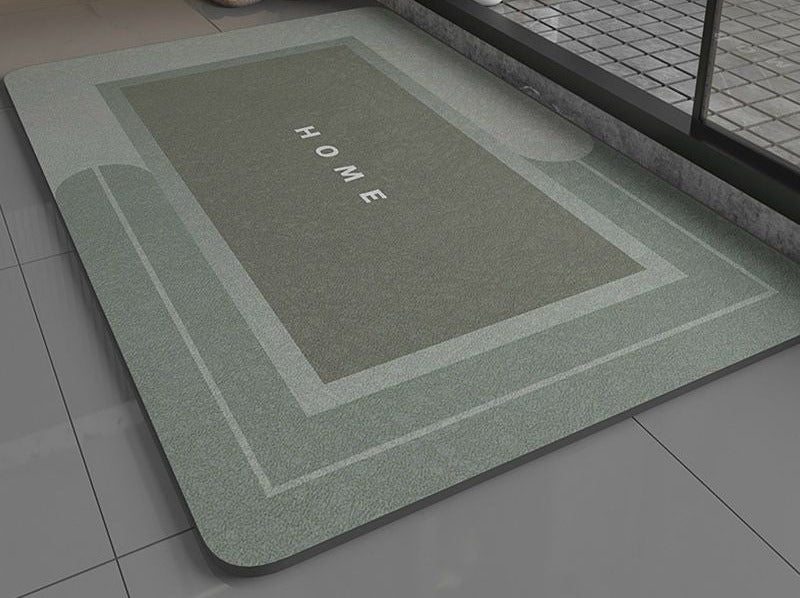 Green super absorbent bath mat with 'HOME' text on a bathroom floor